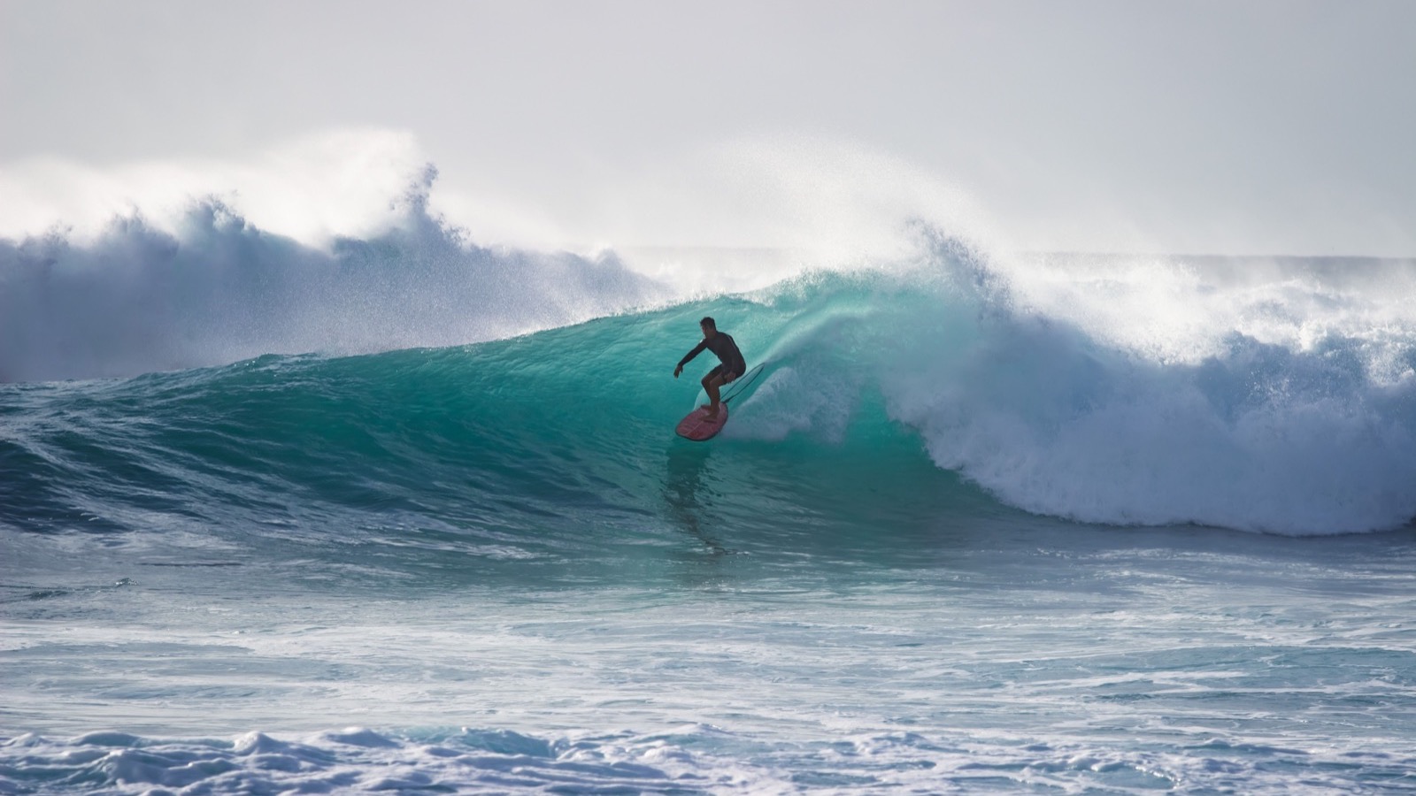 Surfer riding inside a powerful turquoise barrel wave