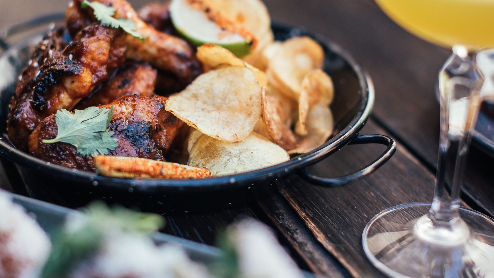 Illustrative stock photo of chicken wings and chips with a cocktail.