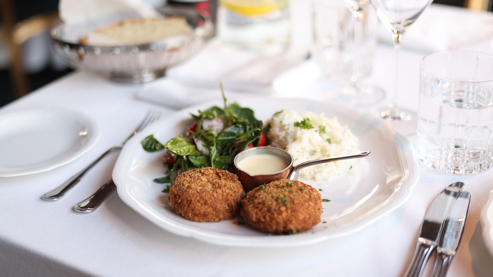 Illustrative stock photo of plated crab cakes in a fine-dining setting.
