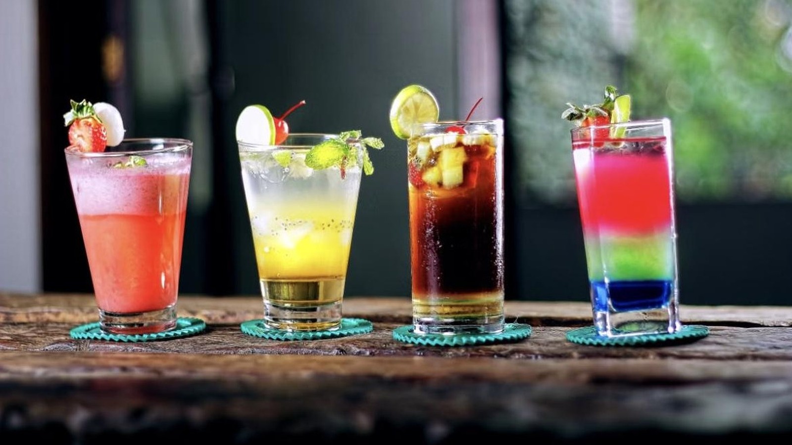 Illustrative stock photo of four cocktails on a wooden surface.