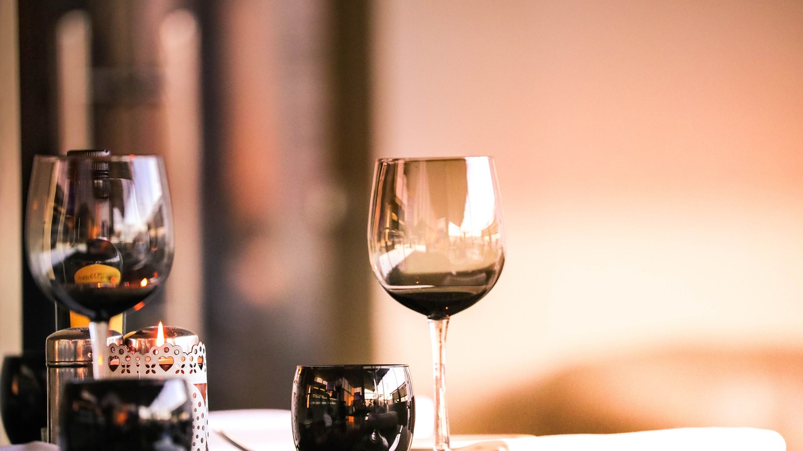 Illustrative stock photo of wine glasses on a candlelit table.