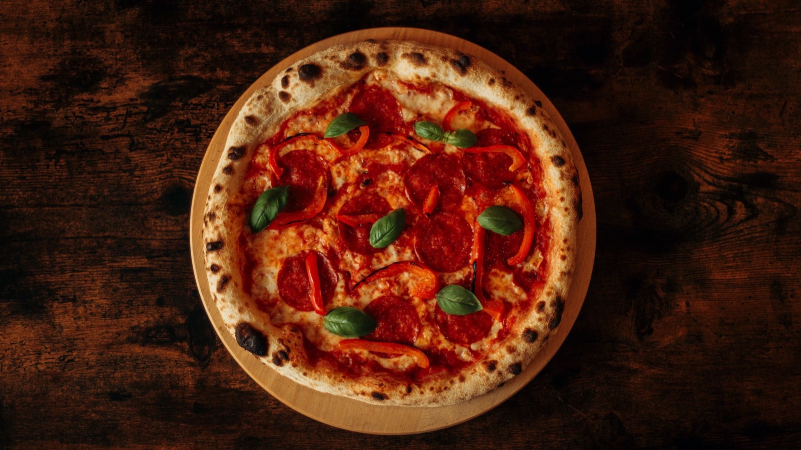 Illustrative stock photo of a wood-fired pepperoni pizza with fresh basil.